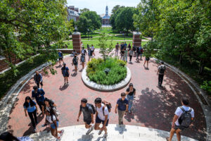 Students walking with a green campus quad in the background