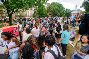 A crowd of students and tables featuring different organizations, outside on a quad.