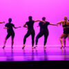 Silhouettes of students dancing on stage.