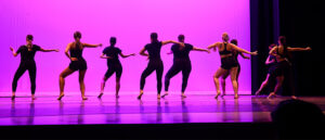 Silhouettes of students dancing on stage.