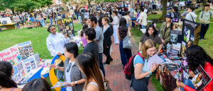 A large crowd of students outside browsing tables and speaking with one another.