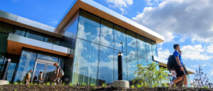 Looking up at a large glass building with students walking in the foreground