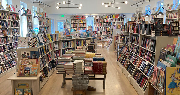 Interior of bookstore, with rows of shelves and geometric light installations hanging from the ceiling.