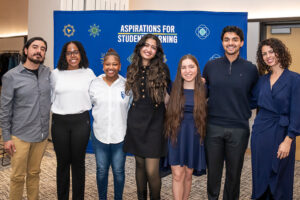 A group of people standing posing for a photo. In the background is a banner that reads "Aspirations for Student Learning"