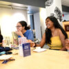 A group of students sitting at a table, sharing a meal and laughing with one another.