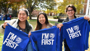 Three students holding up shirts that read "I'm First"