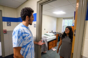 A resident advisor speaking with a student outside their dorm room.