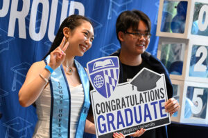 Two students hold up a sign that reads "Congratulations Graduates"